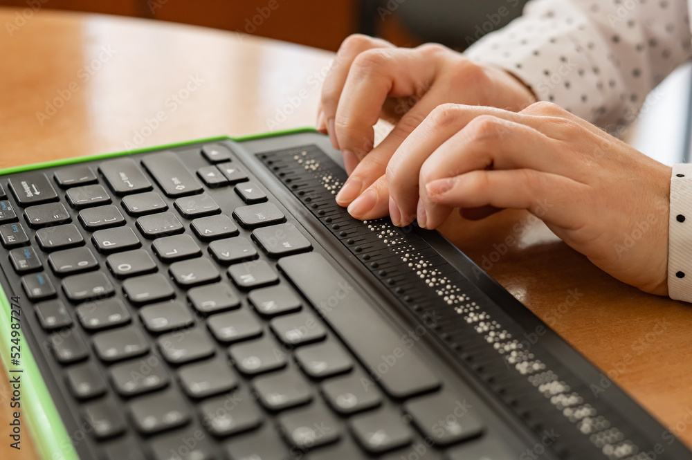 A woman reading and typing brail on her keyboard