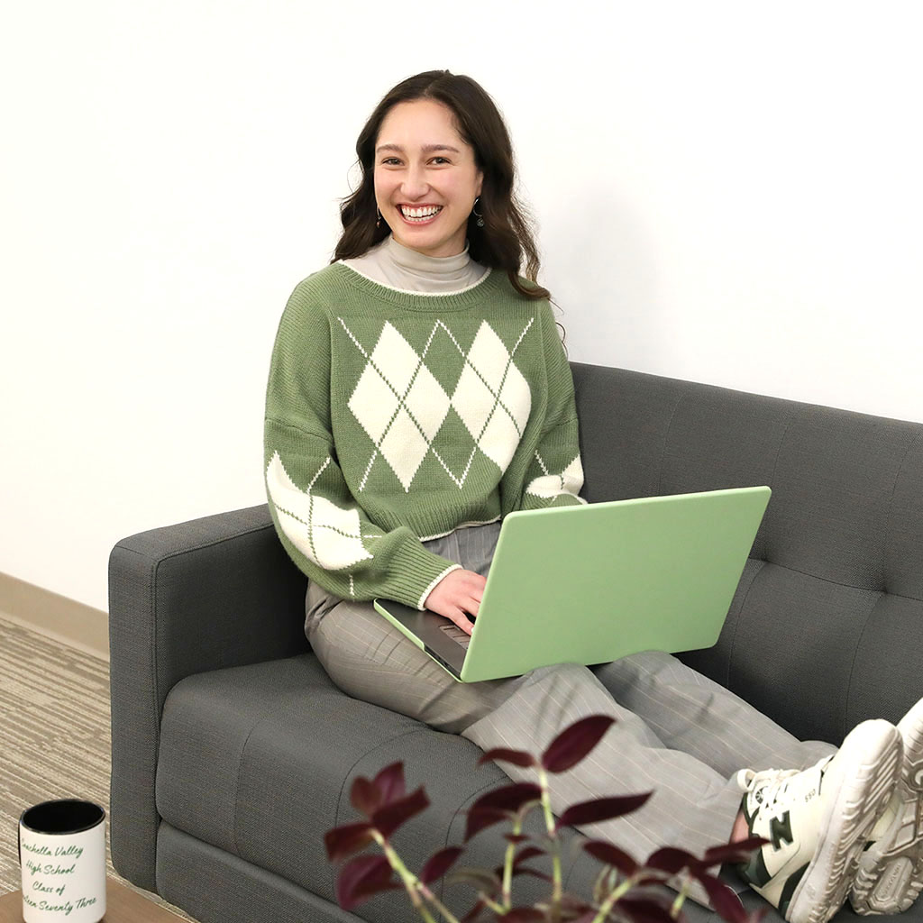 Julia Morgin of 360 Web Designs, smiling as she works sitting with her feet up on a couch